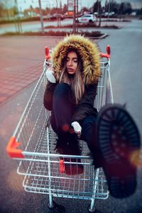 High angle view of young woman sitting in shopping cart on street