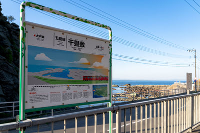 Information sign by railing against blue sky