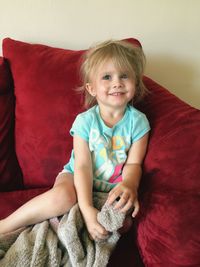 Smiling cute girl sitting on sofa at home