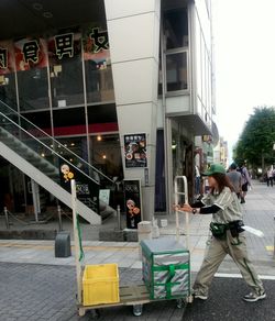 People walking on sidewalk by building in city