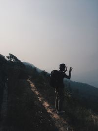 Rear view of man standing on mountain against sky