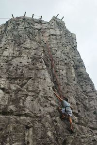 Low angle view of man rock climbing