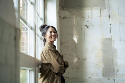 Happy woman with arms crossed leaning on window