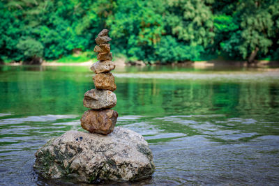 Stack of stones on rock by lake