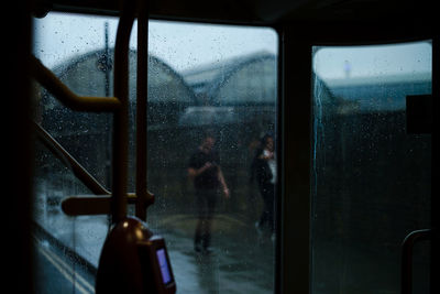 People seen through wet train window in rainy season