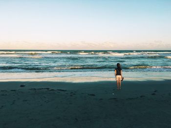 Woman on beach against clear sky