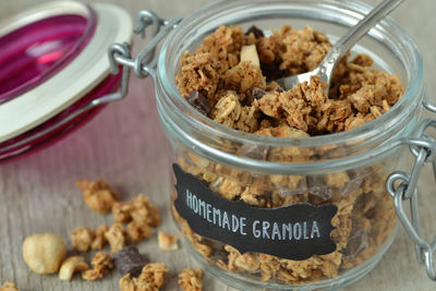High angle view of homemade granola in glass jar with text on wooden table