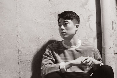 Portrait of young man looking away against wall