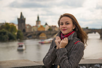 Portrait of woman standing by railing against charles bridge over vltava river