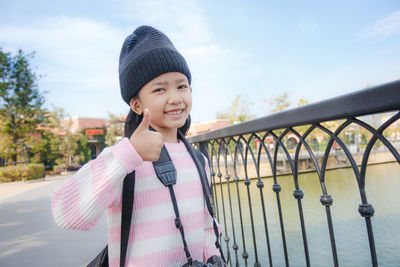 Portrait of smiling girl standing against railing