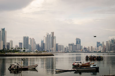 Boats in sea against buildings in city