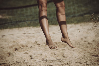 Low section of person jumping at beach