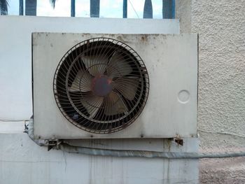 Close-up of electric fan against white wall