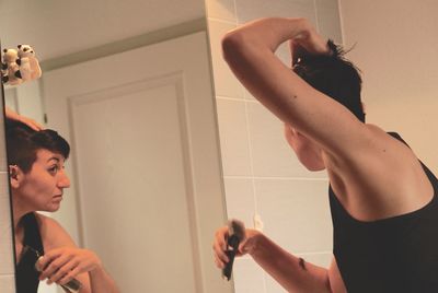 Close-up of young woman standing by mirror