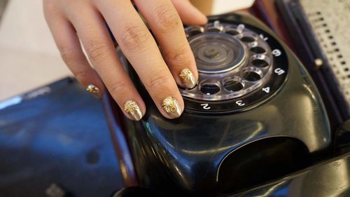 Cropped hand of woman touching rotary phone