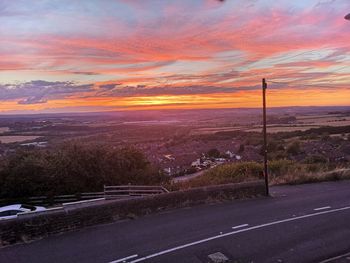 Road by city against orange sky