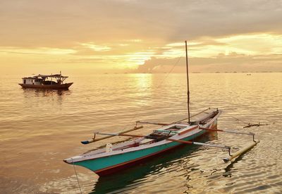 Boat moored in sea against sky during sunset