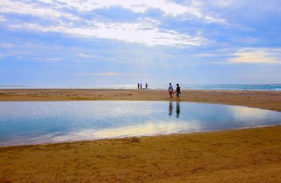 People walking on beach against sky