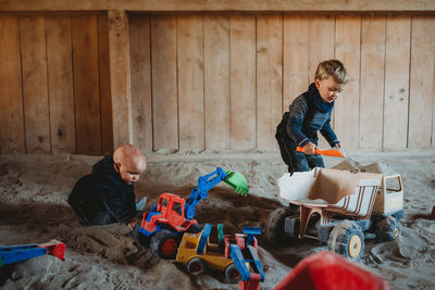 Children playing with trucks and diggers in outdoor sandbox in winter