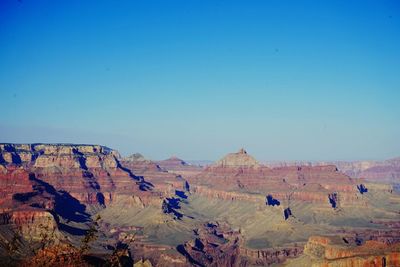 Tourists on mountain against clear blue sky