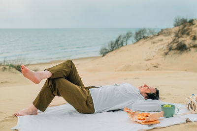 Rear view of woman sitting on sand at beach