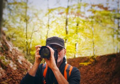 Portrait of man photographing through digital camera in forest