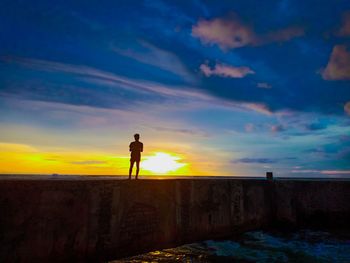 Silhouette man standing against sky during sunset