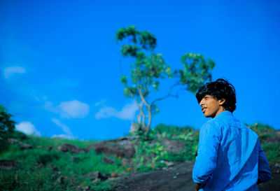 Boy standing against blue sky for a fresh beginning.