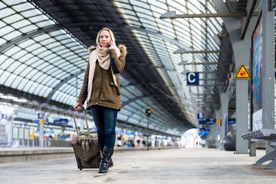 Woman listening over phone while standing at station