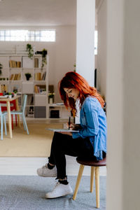 Portrait of young woman sitting on chair at home