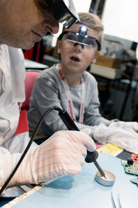 Grandfather and boy repairing computer part on table at home