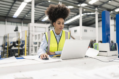 Engineer using laptop at desk in factory