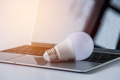 Close-up of light bulb on laptop at table