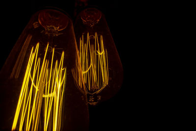 Close-up of illuminated light bulb against black background