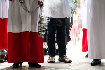 Lower part of catholic church members with incense in the campo santo cemetery church 