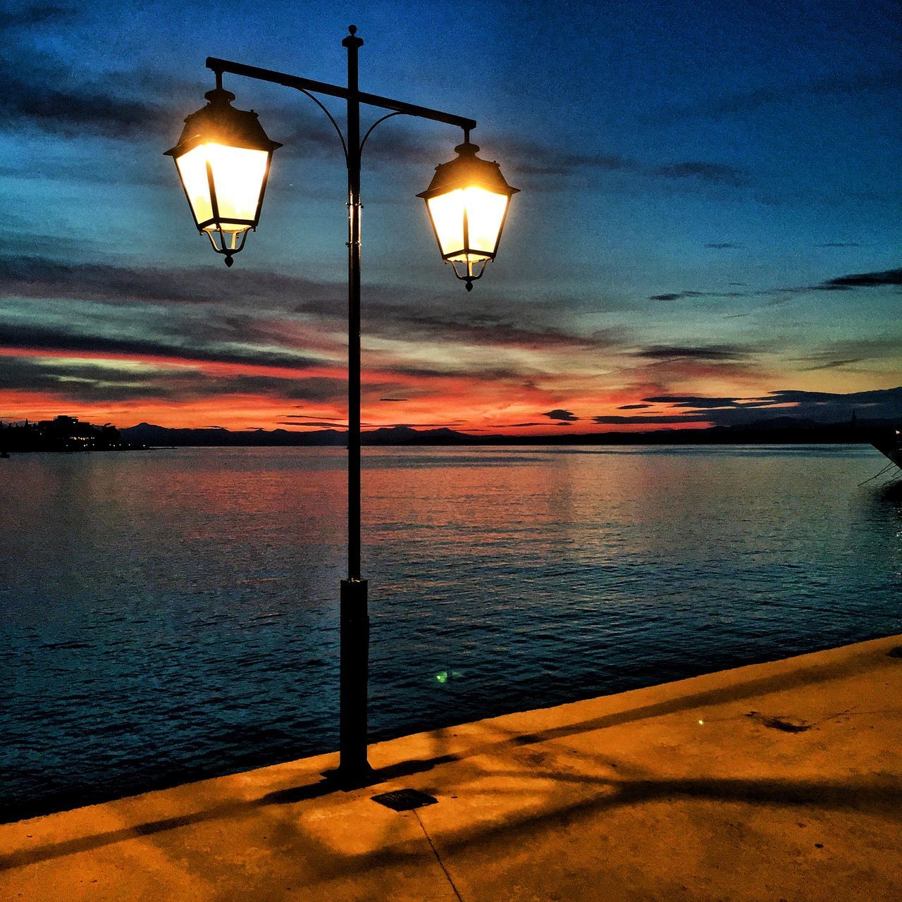 lighting equipment, street light, illuminated, water, sky, electricity, sea, lamp post, sunset, electric light, tranquility, silhouette, reflection, tranquil scene, dusk, scenics, pole, lamp, night, nature