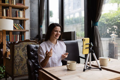 Happy young caucasian millennial or gen z woman with long brunette hair streaming with smart phone 