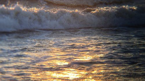 Close-up of sea waves against sky during sunset