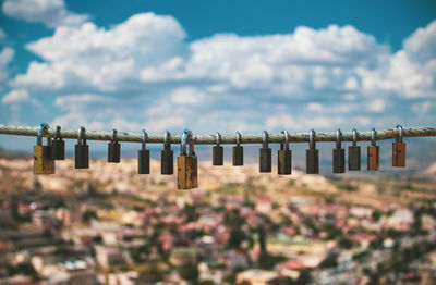 Padlocks hanging on metal structure against sky