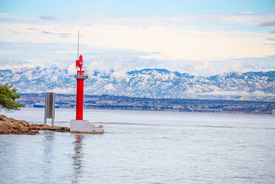 Lighthouse by sea against sky