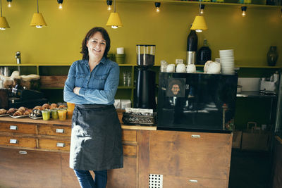 Portrait of confident female owner standing in coffee shop