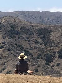 Rear view of man sitting on mountain road