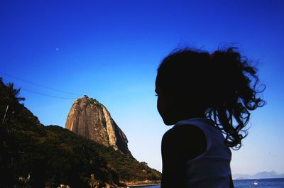 Girl looking at sugarloaf mountain against clear blue sky