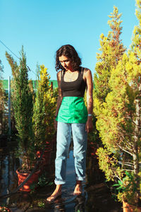 Portrait of young woman standing against plants
