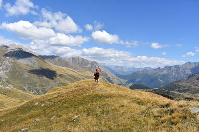 Rear view of man walking on mountain against sky