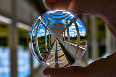 Cropped hand holding crystal ball with reflection of walkway