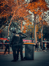 Rear view of people walking on street during autumn