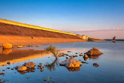 Scenic view of lake against clear sky during sunset