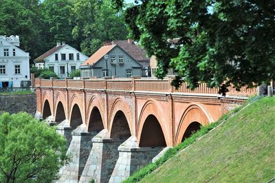 Arch bridge over river amidst trees and buildings