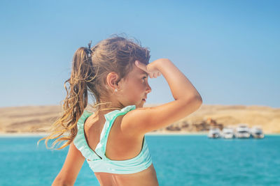 Side view of woman standing at beach against sky